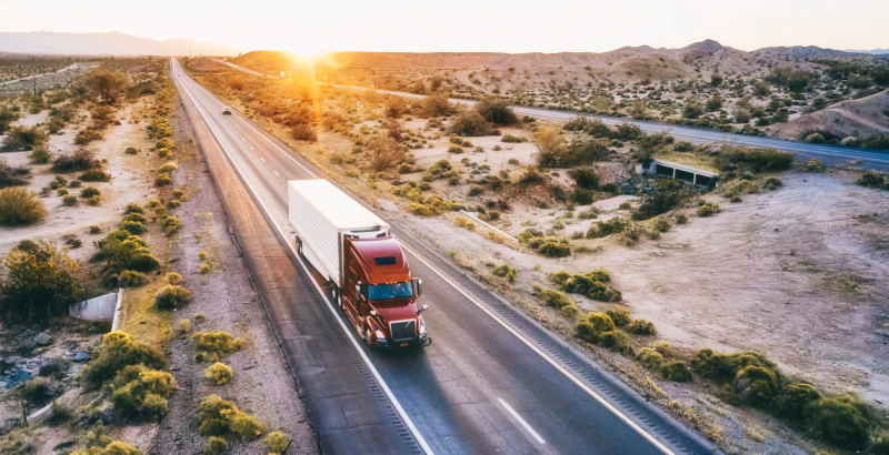 Truck on desert road at sunset